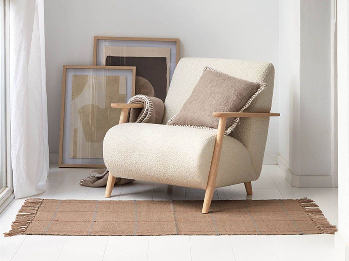 a chair with a pillow on it sits next to a rug