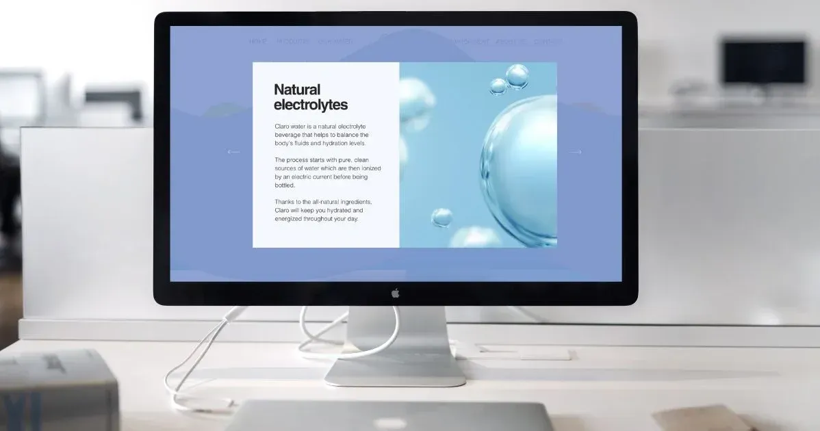 A computer monitor is sitting on a desk with a website about water bottles on screen. Water company