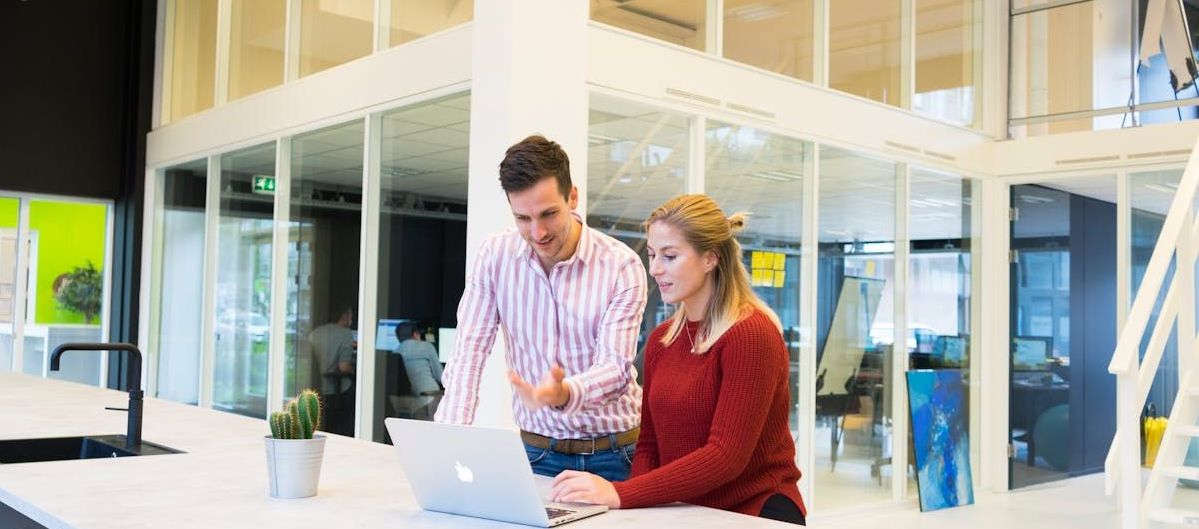A man and a woman are looking at a laptop computer.