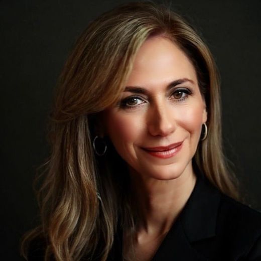 A woman wearing hoop earrings and a black jacket smiles for the camera