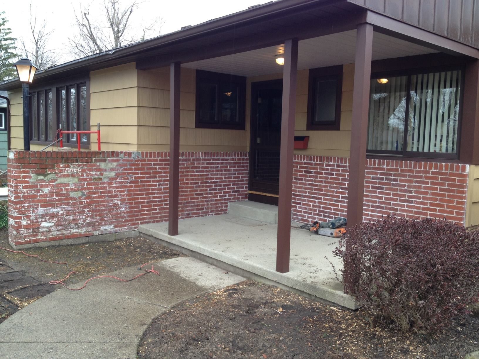A single-story building with a covered porch; brick pillars and walkway lead to the entrance.