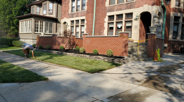 Brick house with a small porch, blue awning, and stamped concrete pathway leading to the front door.
