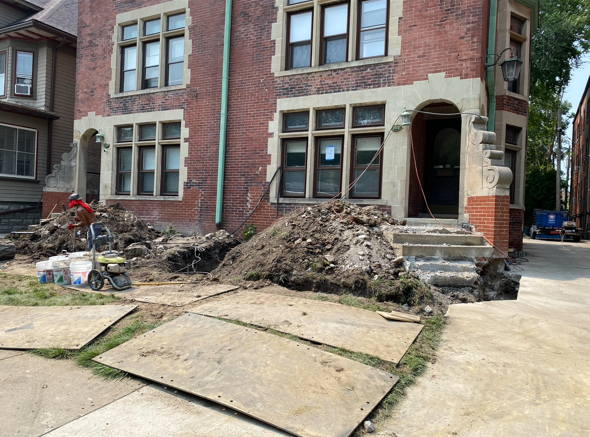 Brick rowhouse with piles of dirt and debris along the front walkway and sidewalk during construction work