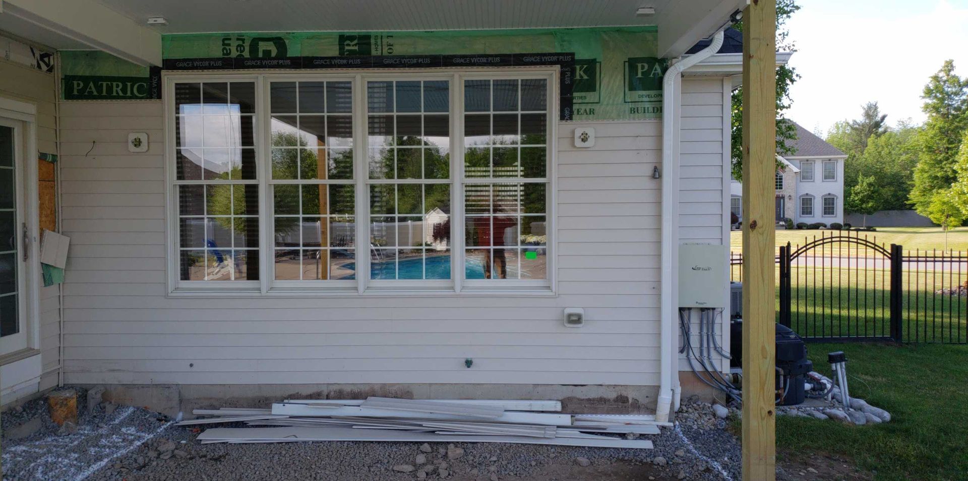 Front of a small building with a window, door, porch column, and damaged concrete steps in daylight