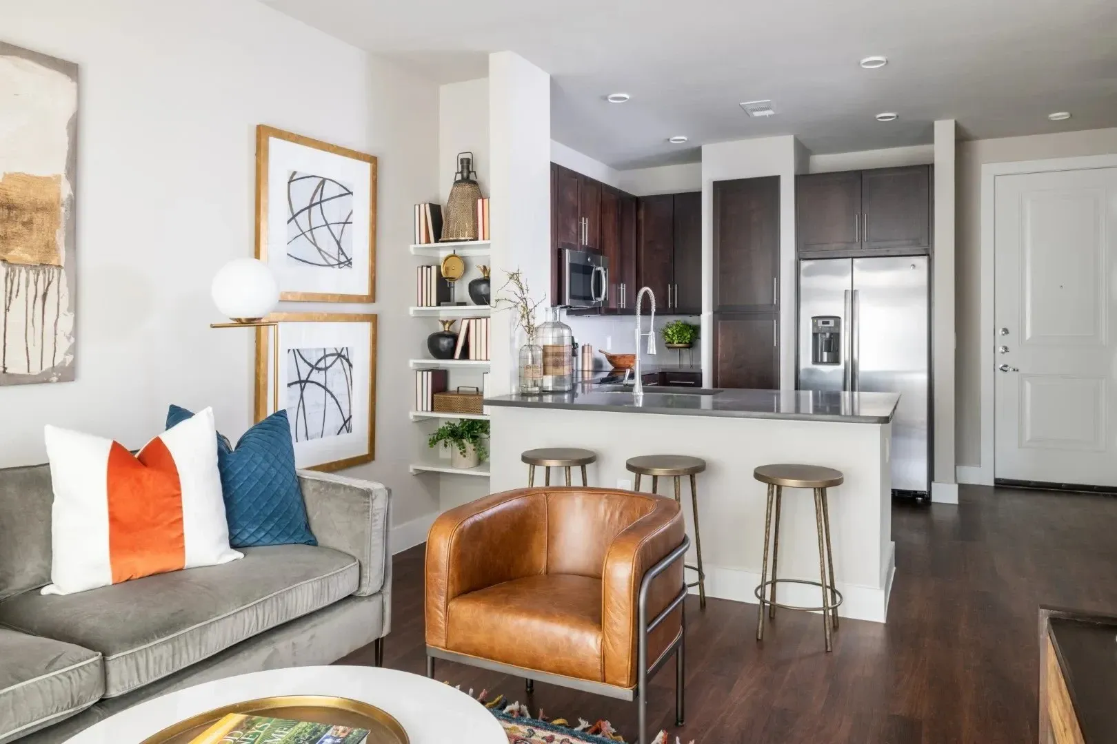Stylish apartment interior featuring a living room with sofa, accent chair, and kitchen area