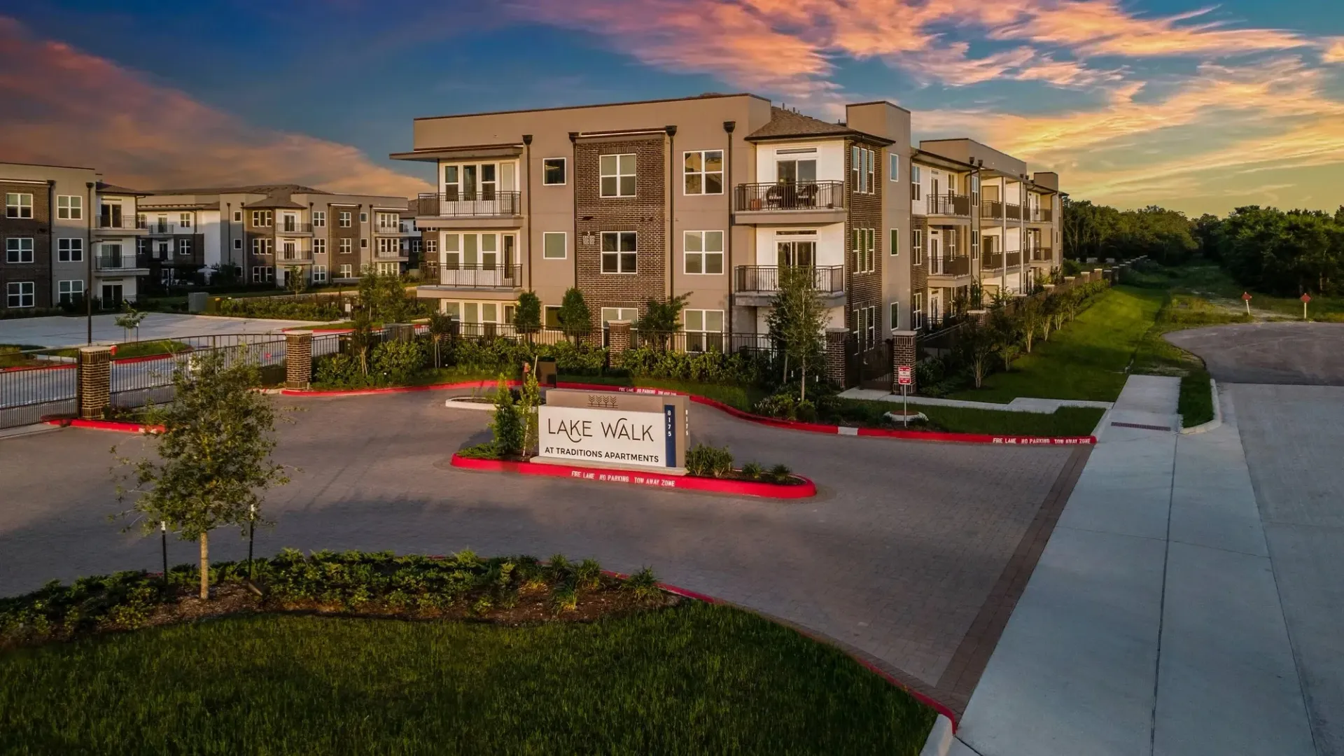 Exterior view of Lake Walk at Traditions Apartments with landscaping and signage