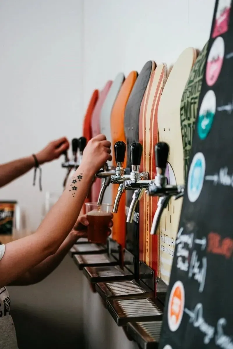 People pouring drinks from a tapped beverage wall