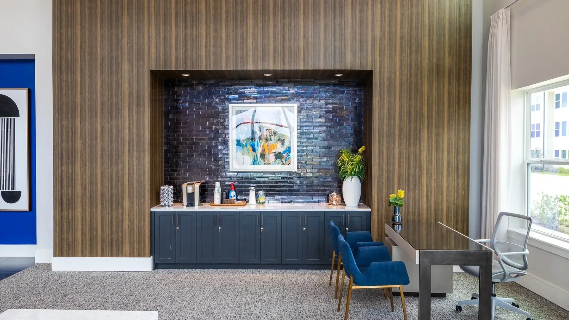 Interior lounge area with dark blue wall, artwork, and seating.