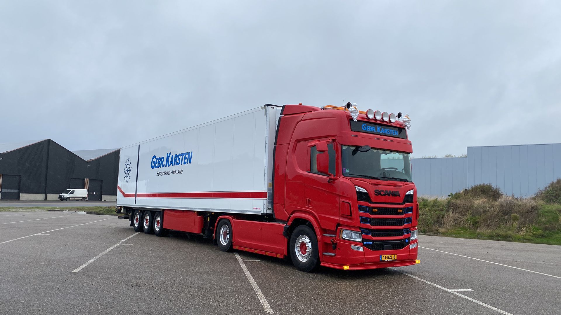 Rode vrachtwagen met witte aanhanger; geparkeerd op de stoep. Bewolkte dag. 