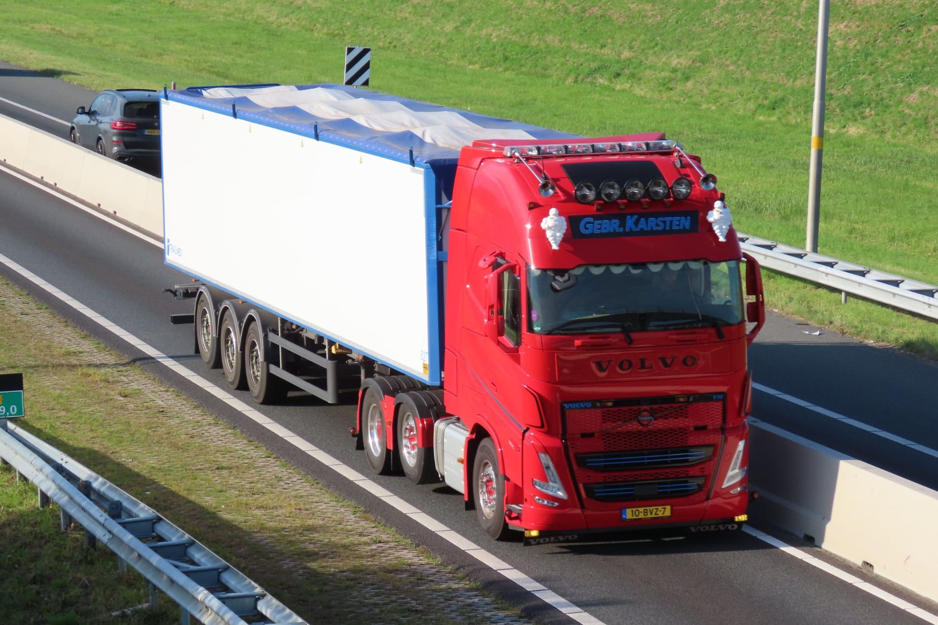 Rode Volvo-vrachtwagen met witte oplegger op de snelweg.