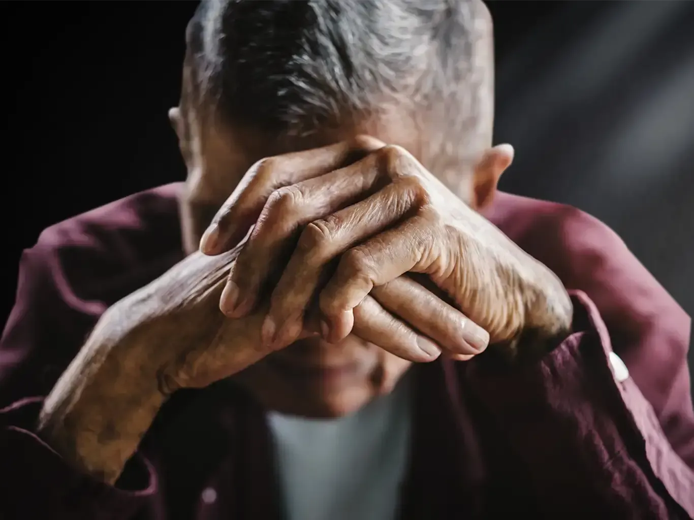 Grieving person covering his face with his hands learning how to cope with loss.
