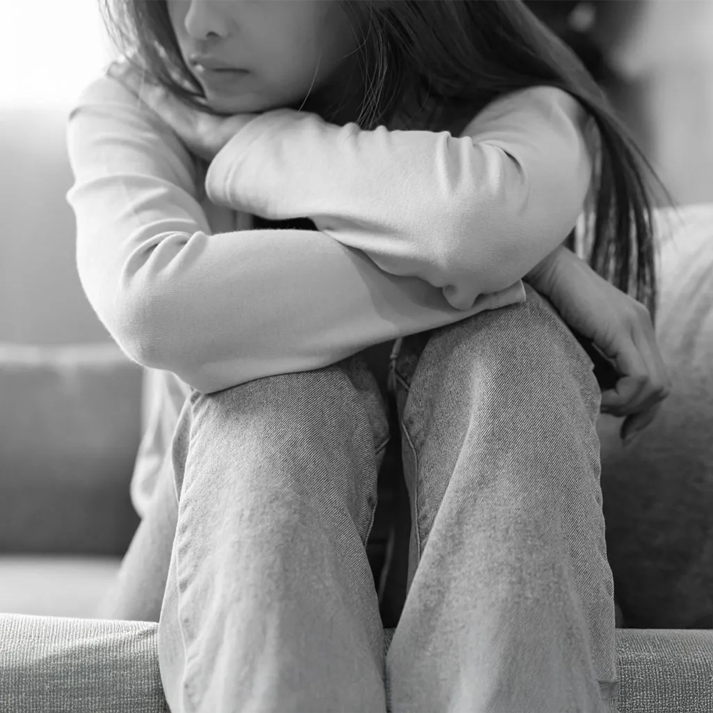 Individual Therapy for Healing and Growth Young woman sitting with knees pulled to her chest, reflecting the emotional struggles individual therapy can help address.