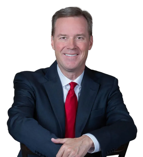 A man in a suit and tie is sitting with his arms crossed