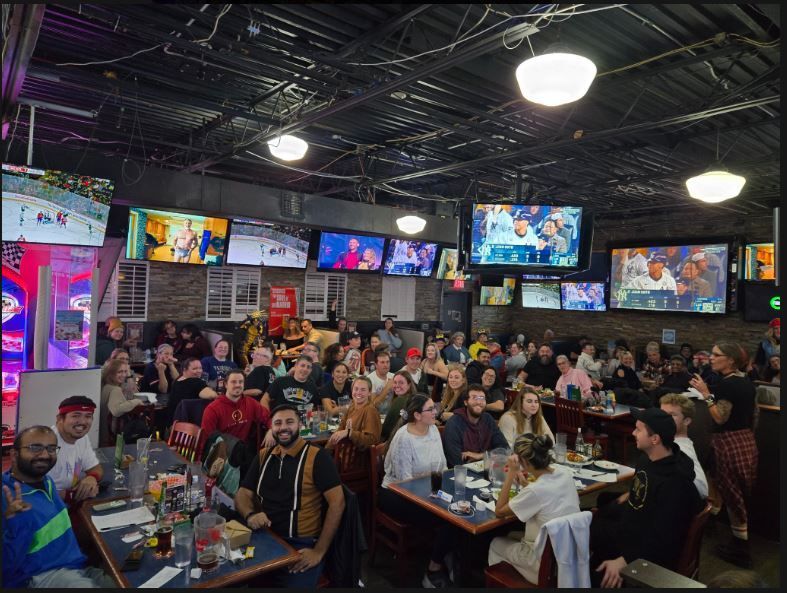 Crowded sports bar with many people watching multiple TVs and dining at tables