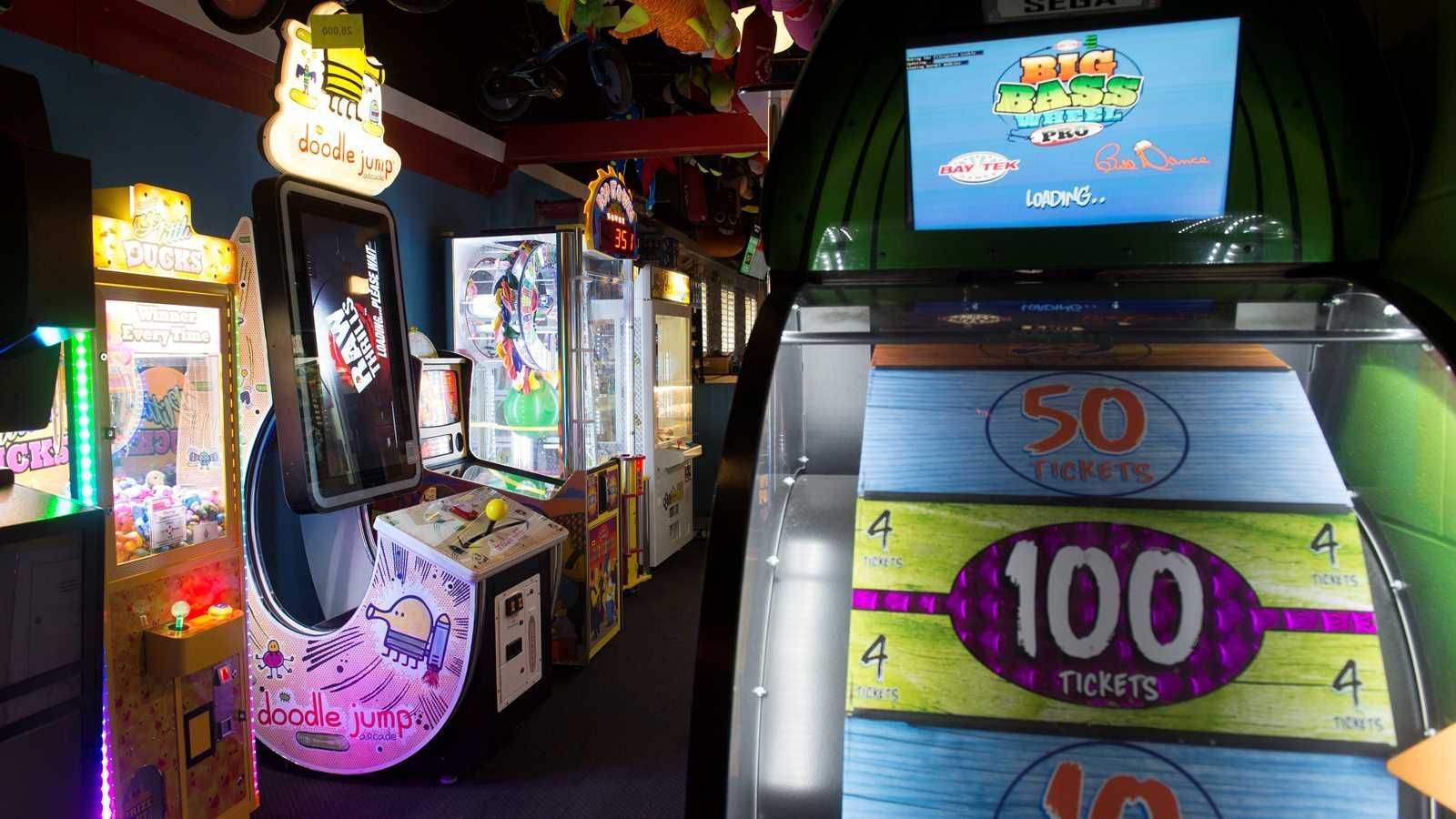 Arcade with colorful prize machines and a game screen showing a 100-point target on the right