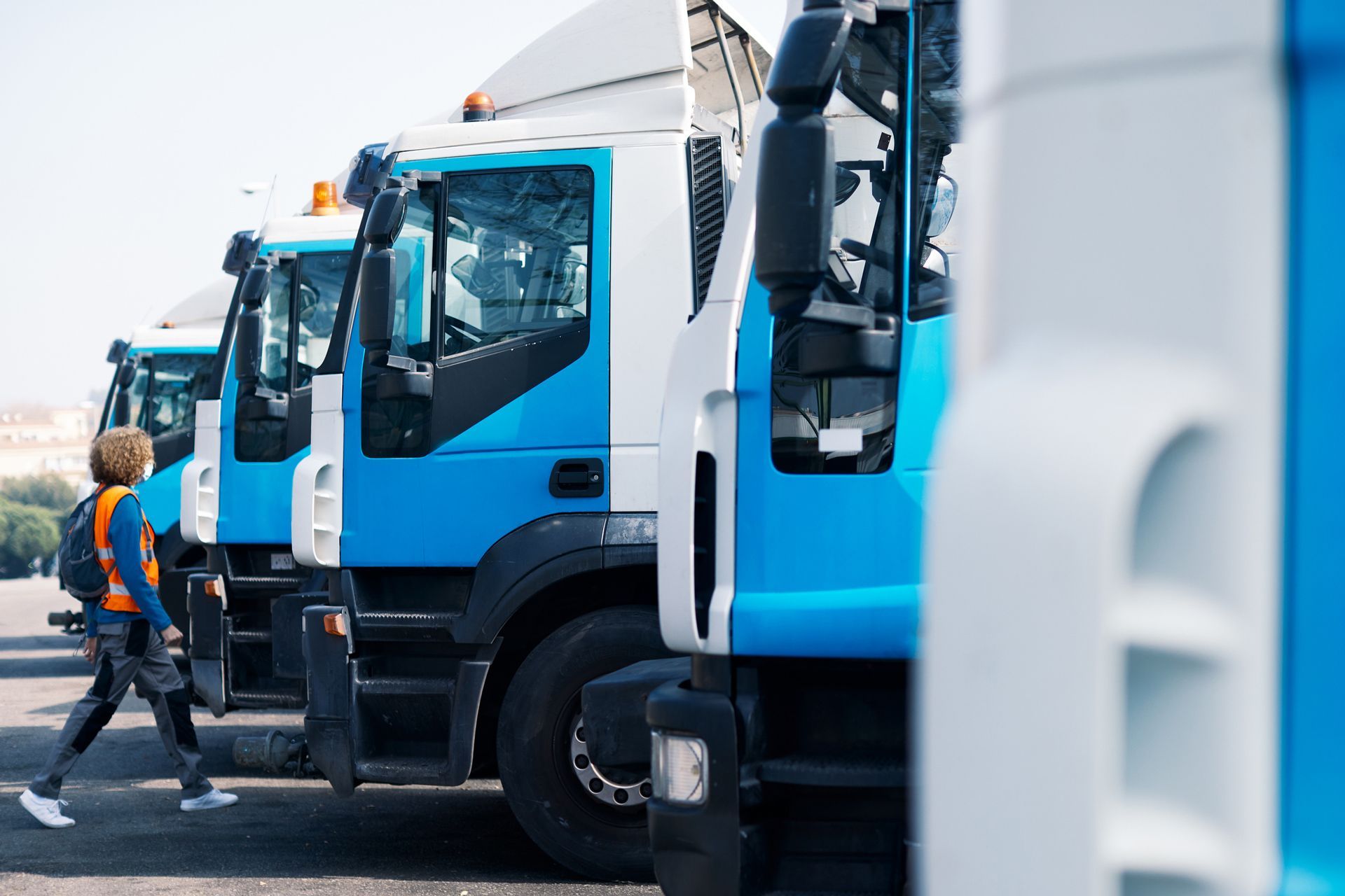 A woman is walking past a row of blue and white trucks.