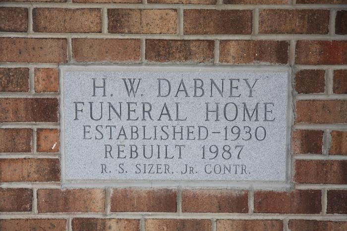 A stone plaque on a brick wall reads: H.W. DABNEY FUNERAL HOME, ESTABLISHED-1930, REBUILT 1987, R. S. SIZER, JR. CONTR.