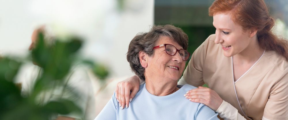 Caregiver Smiling and Comforting an Older Person — Home Nursing Services in Liverpool, NSW