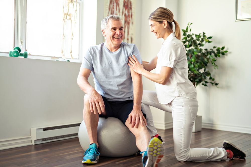 Physical Therapist Helping a Seated Patient Exercise — Home Nursing Services In Laurieton, NSW