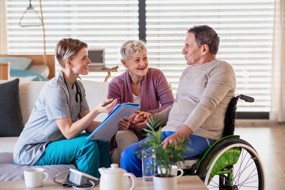 A Nurse is Talking to an Elderly Couple and a Man in a Wheelchair — Home Nursing Services In Port Macquarie, NSW
