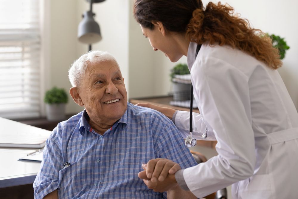 A Doctor is Holding the Hand of an Elderly Man — Home Nursing Services in Laurieton, NSW