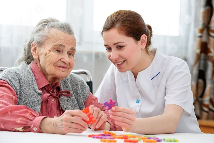 A Nurse is Helping an Elderly Woman With a Puzzle — Home Nursing Services In Port Macquarie, NSW