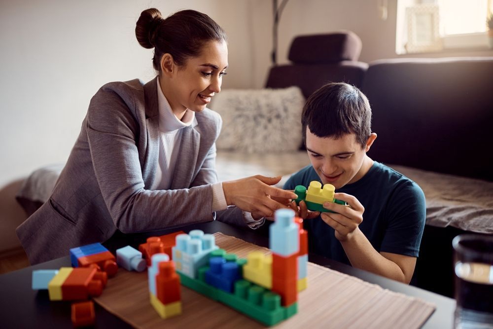 A Woman and a Boy Are Playing With Blocks at a Table — Home Nursing Services In Port Macquarie, NSW