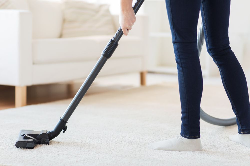 Person Vacuuming a Light Carpet in A Bright Living Room — Home Nursing Services in Liverpool, NSW
