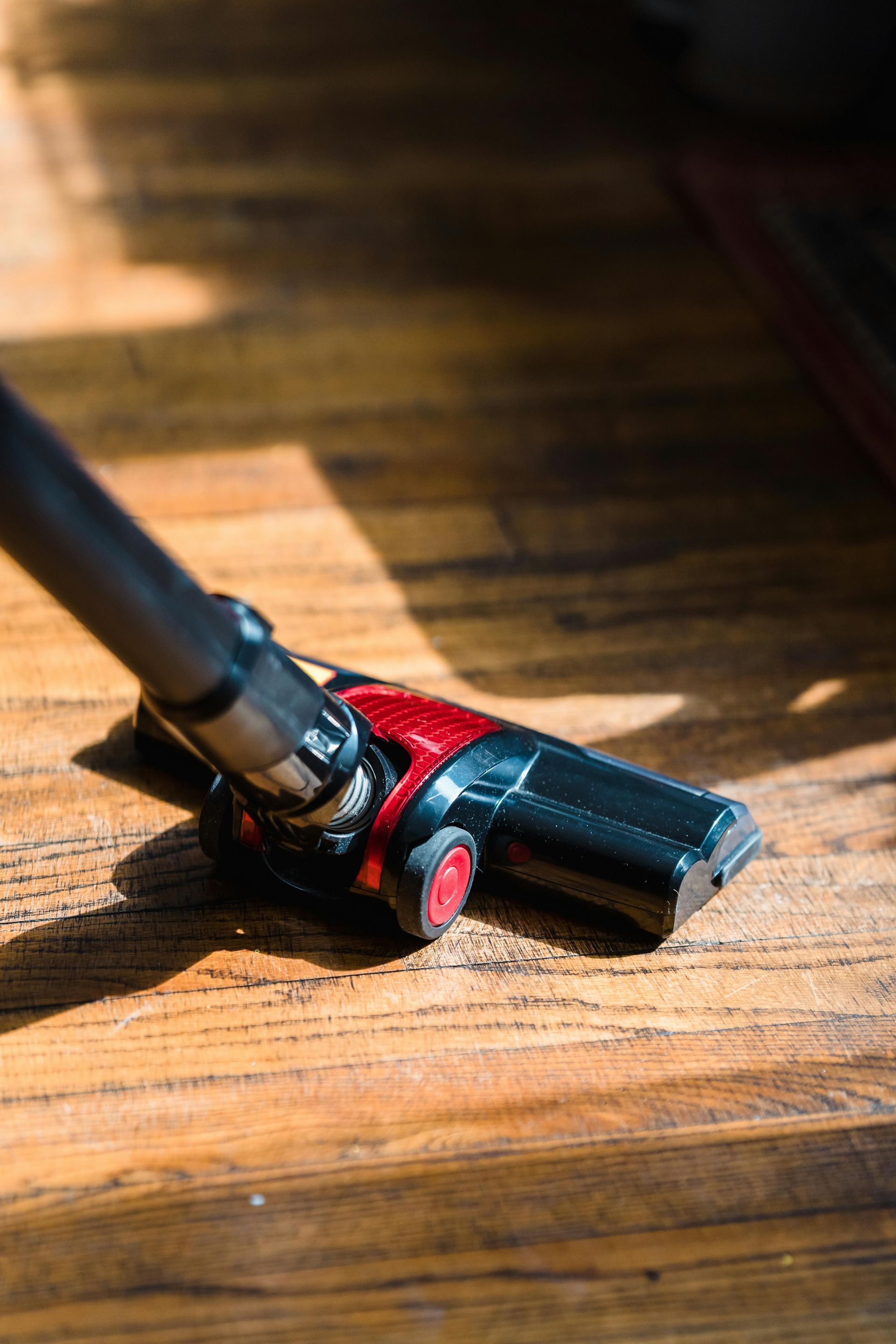 Cordless Vacuum Cleaner Head Cleaning a Sunlit Wooden Floor — Home Nursing Services in Campbelltown, NSW