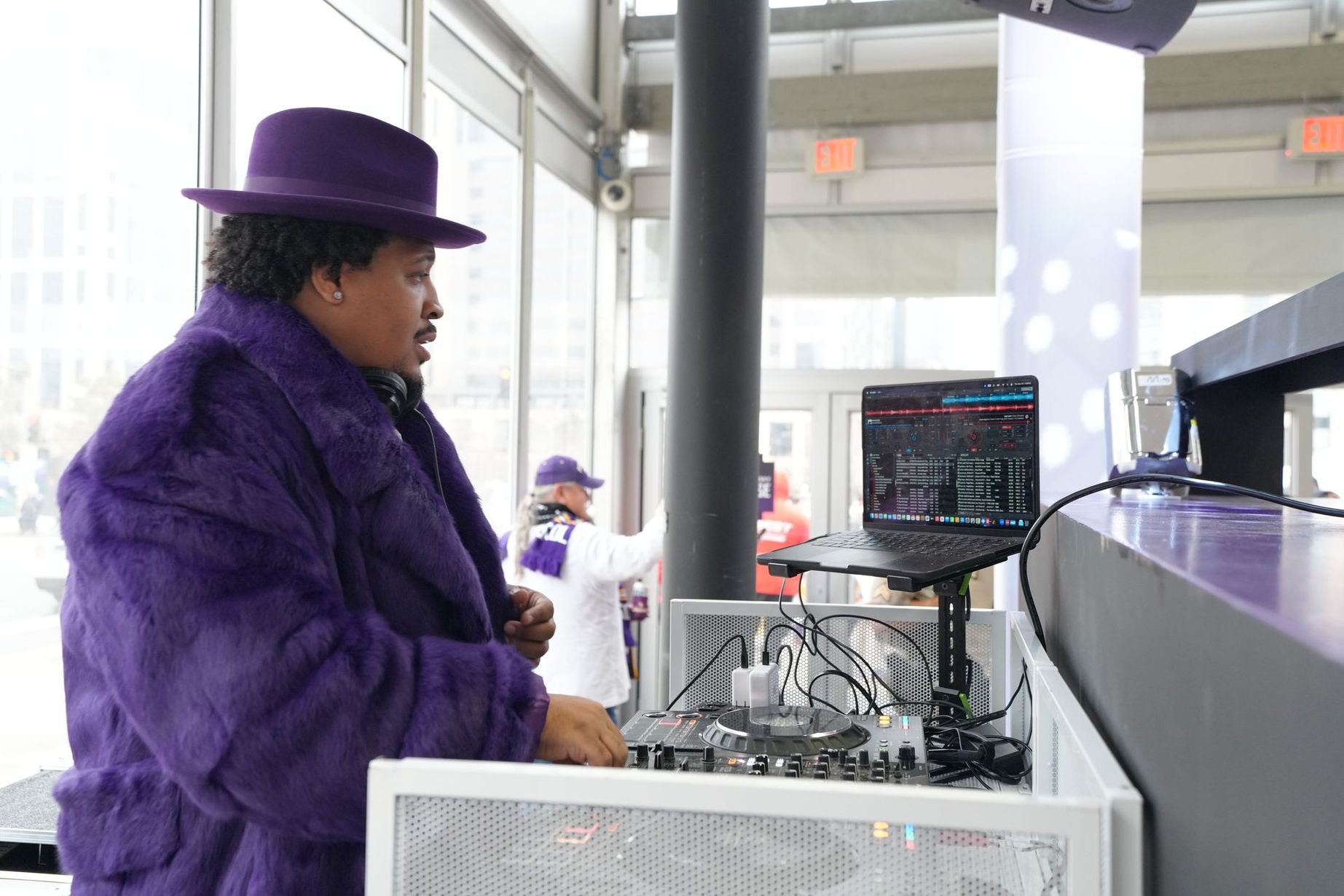 Person in a purple suit and hat operating industrial machinery in a factory-like setting