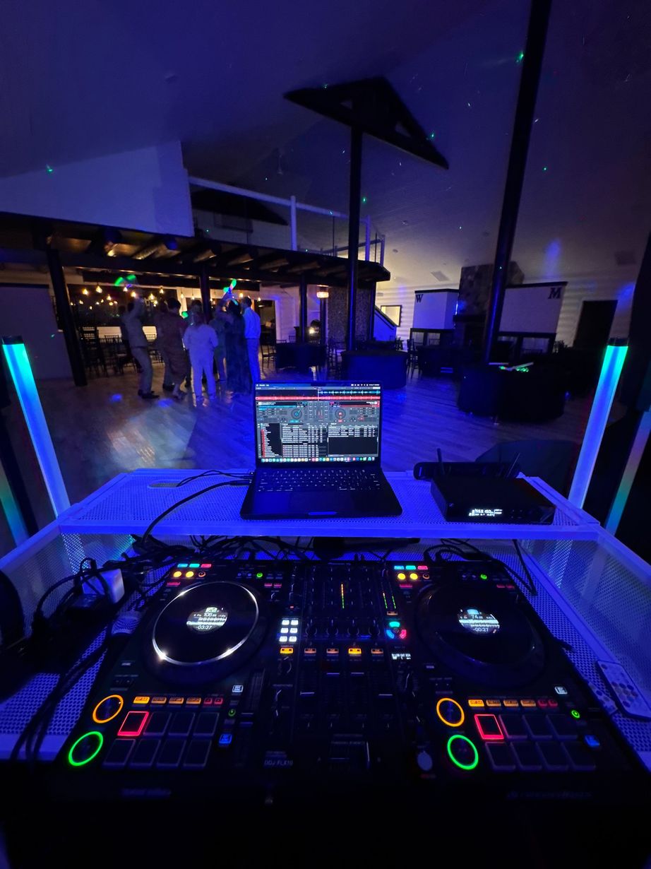 DJ booth with glowing controls and laptop at a dimly lit nightclub event