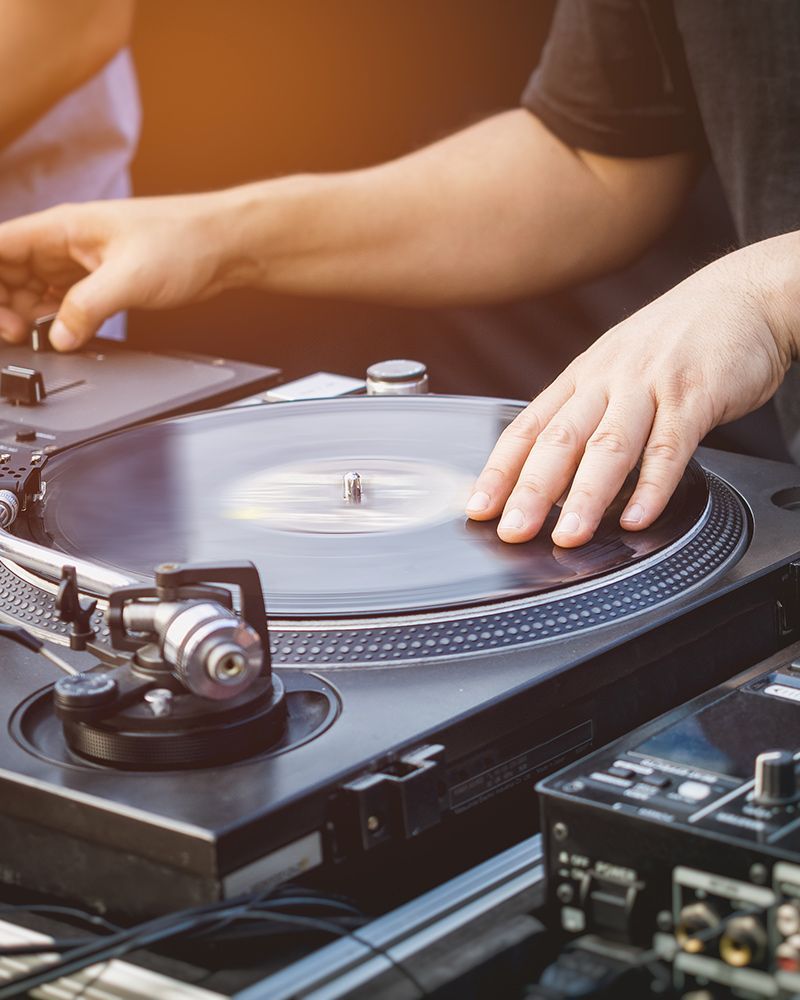 Hands adjusting a vinyl record on a turntable during a DJ setup