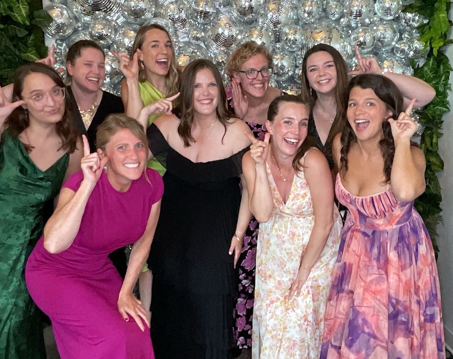 Group of friends posing and smiling at a party in front of a silver balloon backdrop