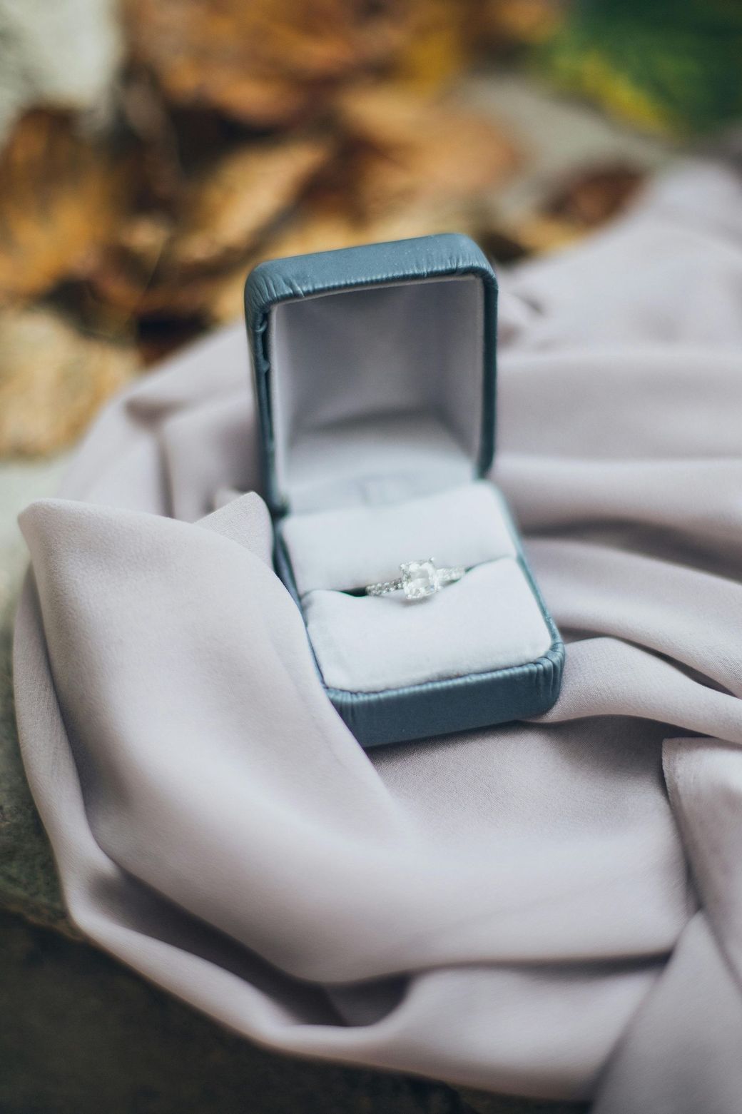 A close up of a ring in a box on a cloth.