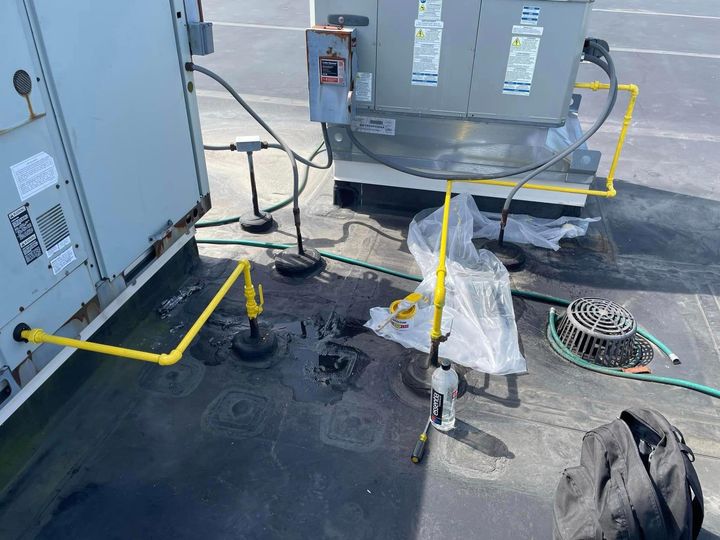 A man is working on a rooftop air conditioner.