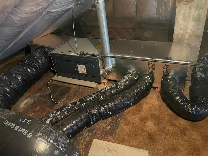 A bunch of black pipes are connected to a machine in a room.