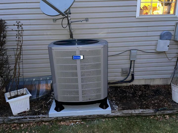 An air conditioner is sitting on the side of a house next to a window.
