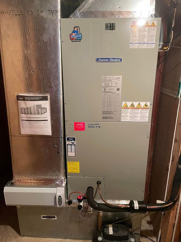 An air conditioner is sitting in a basement next to a wall.
