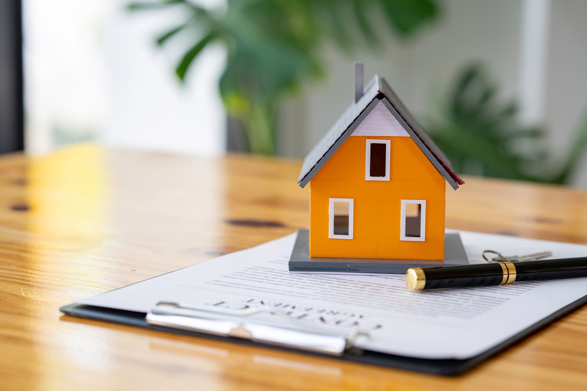 Miniature orange house model on top of a real estate contract