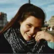 Um close de uma mulher usando um lenço e sorrindo.