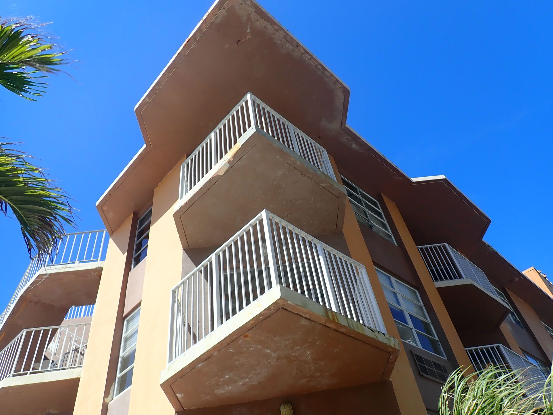 Stacked condominium balconies with staining and cracked stucco, the conditions a Boca Raton milestone inspection documents, recorded by M&P Consulting Engineers