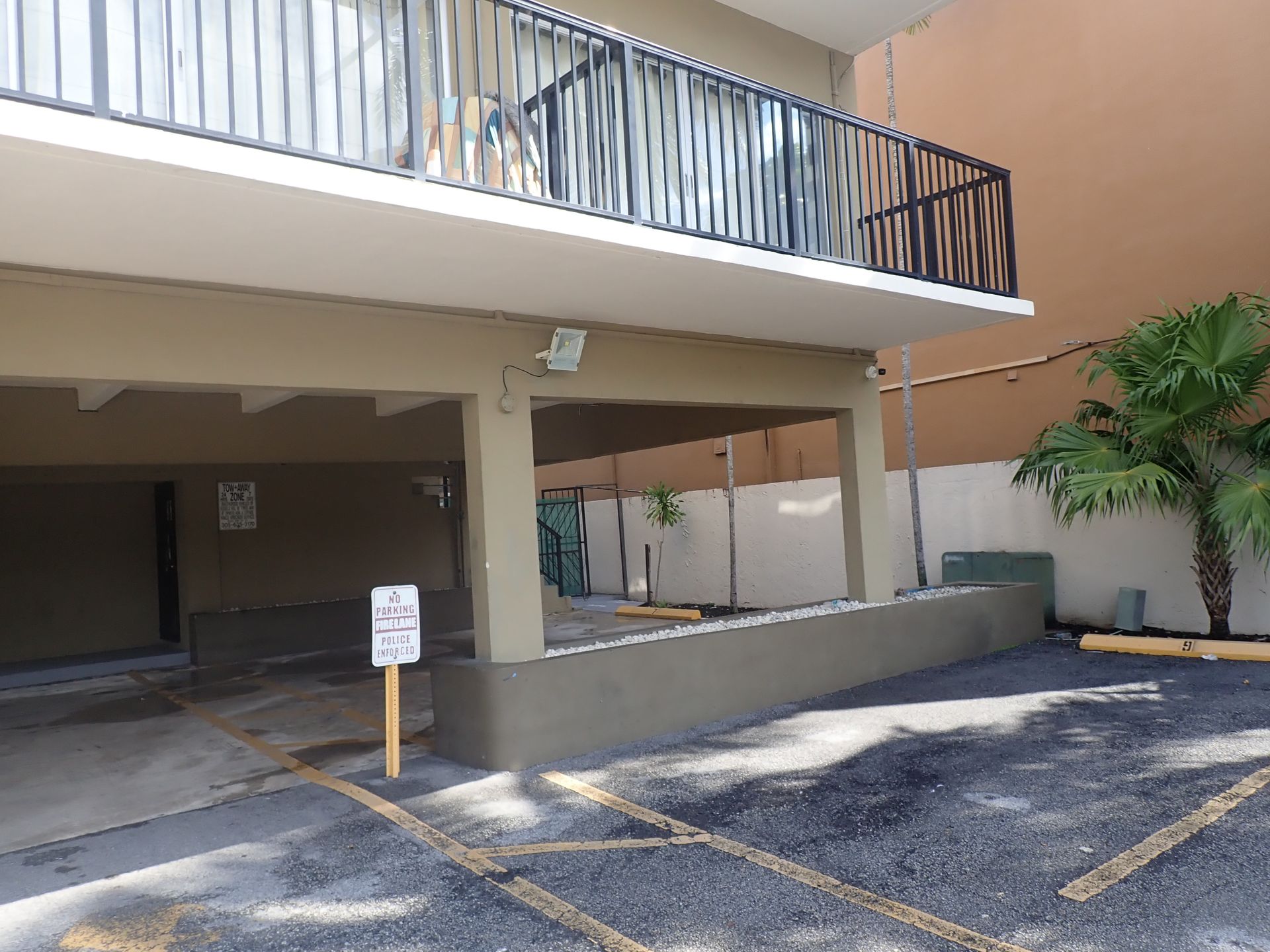Ground-level covered parking area and balcony overhang of a Sunny Isles Beach high-rise, with 'No Parking Fire Lane' signage, during a milestone inspection by M&P Consulting Engineers