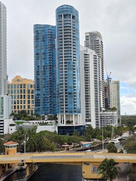 Blue and white high-rise towers beside a canal under a cloudy sky