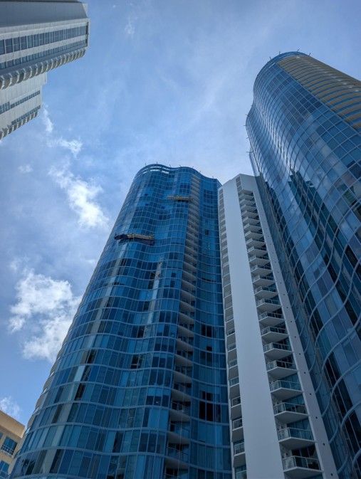Looking up at tall blue glass skyscrapers against a partly cloudy sky