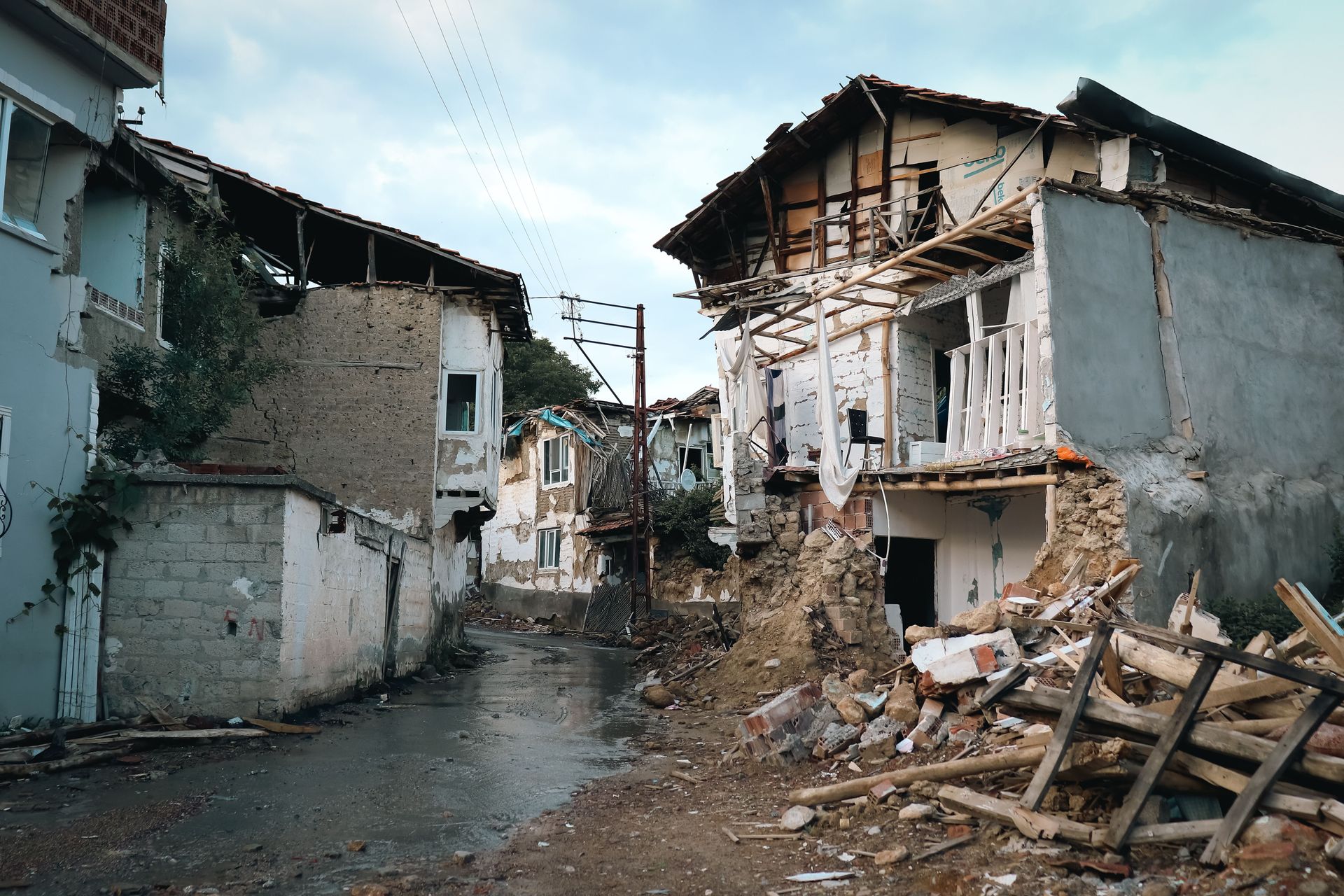 Damaged buildings and rubble along a narrow street after an earthquake or disaster