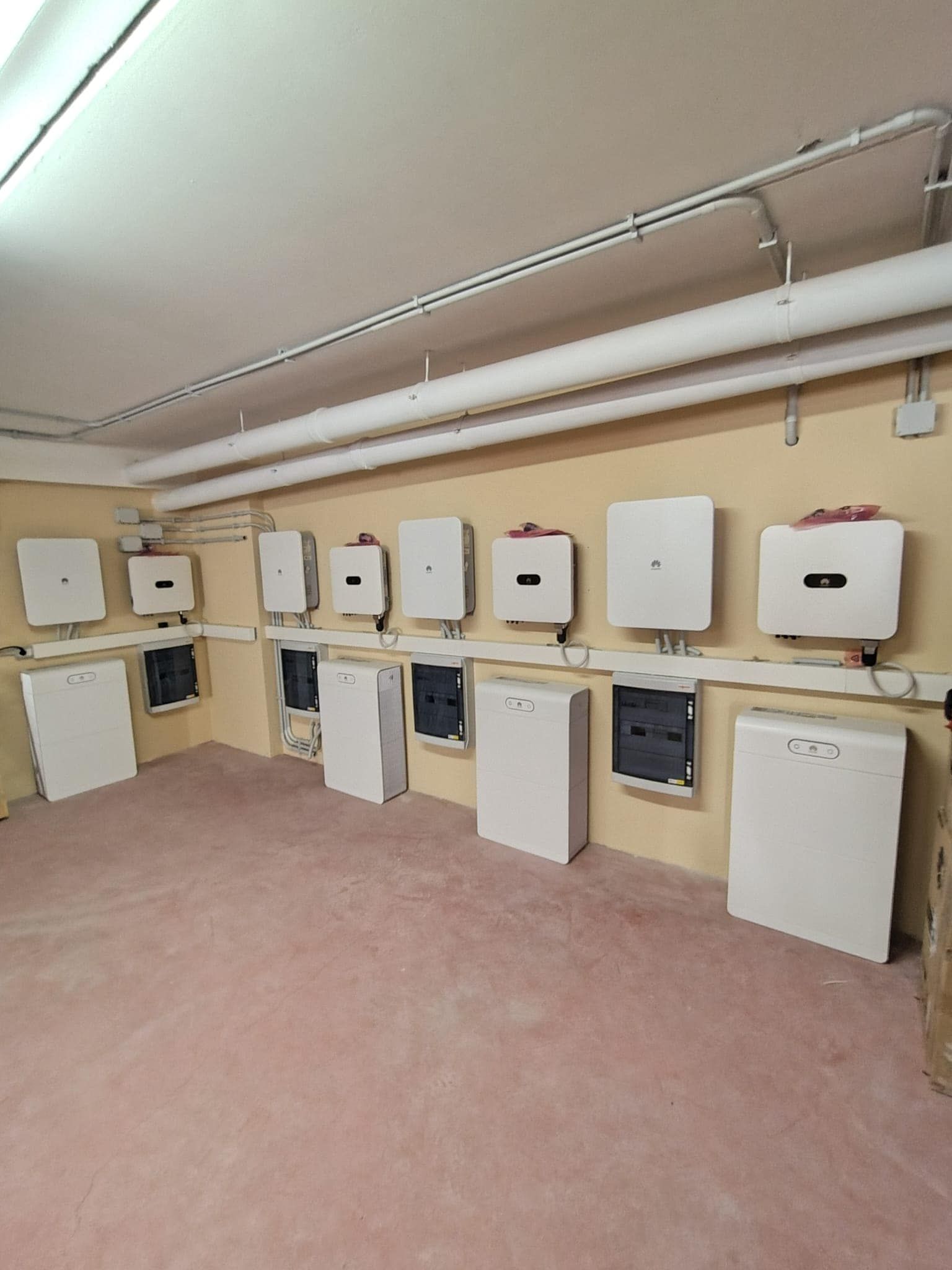 Locale tecnico nel seminterrato con diverse caldaie bianche a parete e tubature lungo la parete