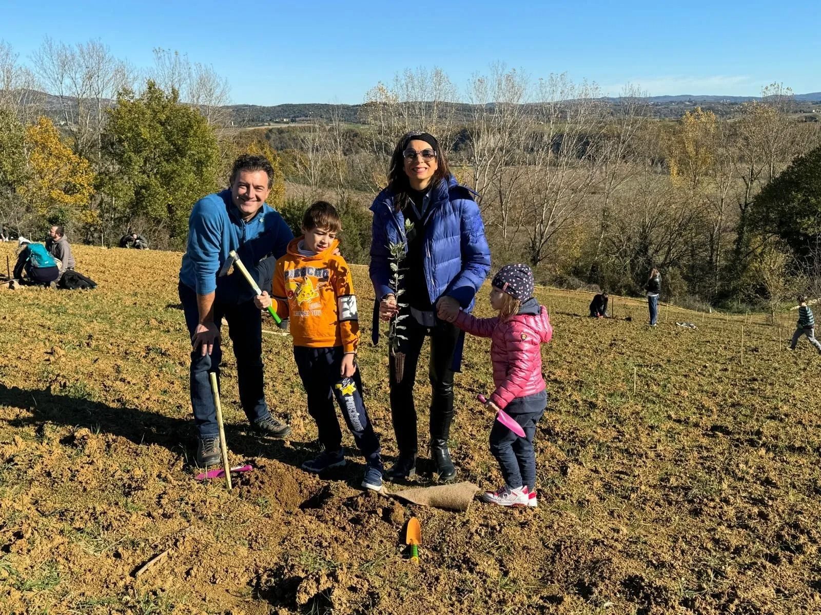 Quattro persone in posa in un campo con alberi sullo sfondo, con in mano dei bastoni da passeggio, in una giornata di sole.