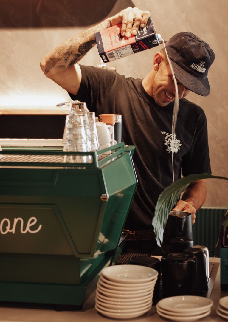 A Man With a Beard is Wearing a Black Shirt and Apron — Barber Bros & Co - Southport in Southport, QLD