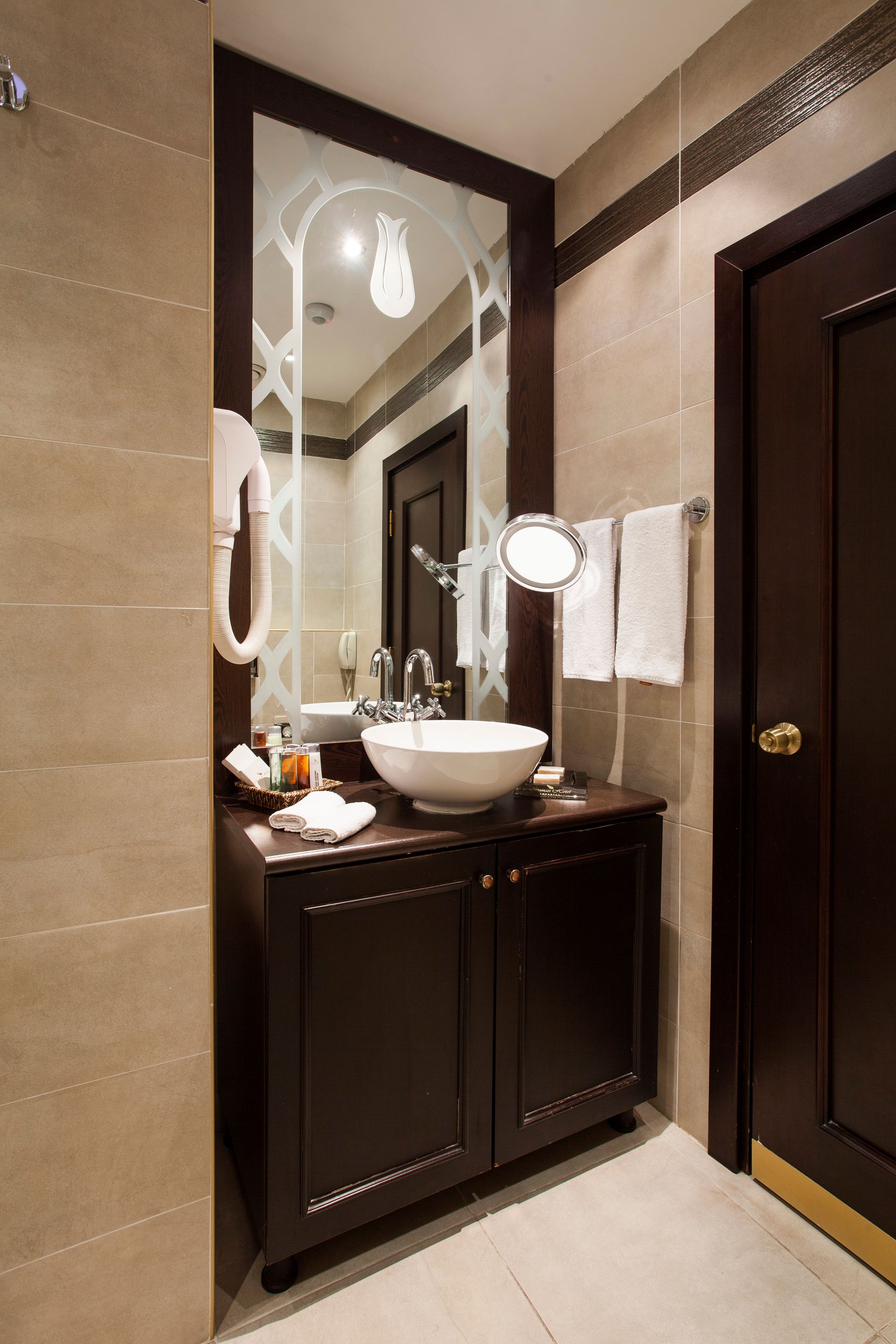Ottoman Hotel Imperial| sultan room Bathroom with dark brown vanity, white sink, large mirror, and brown door.