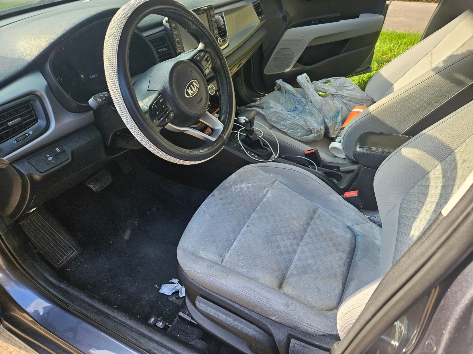 The inside of a dirty car with a steering wheel and seats.